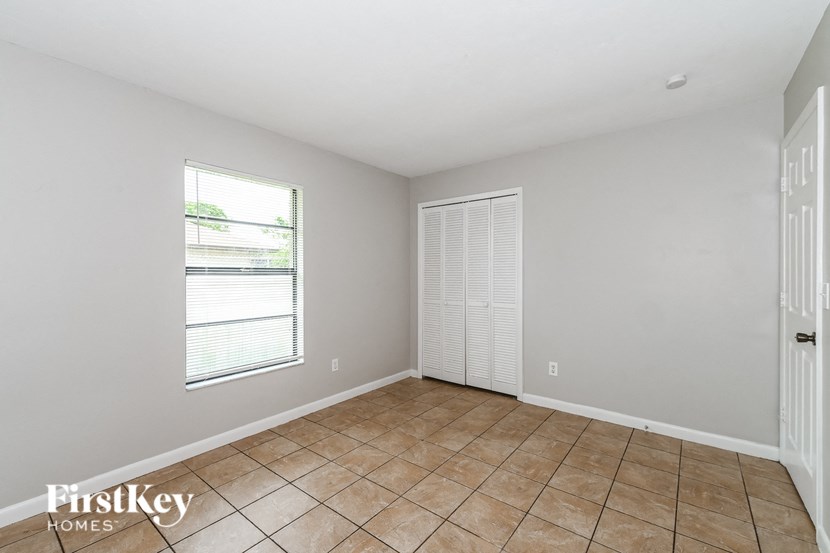 an empty living room with a large window and tiled floors