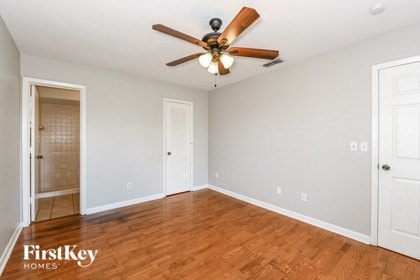 an empty living room with a ceiling fan and a door to a closet