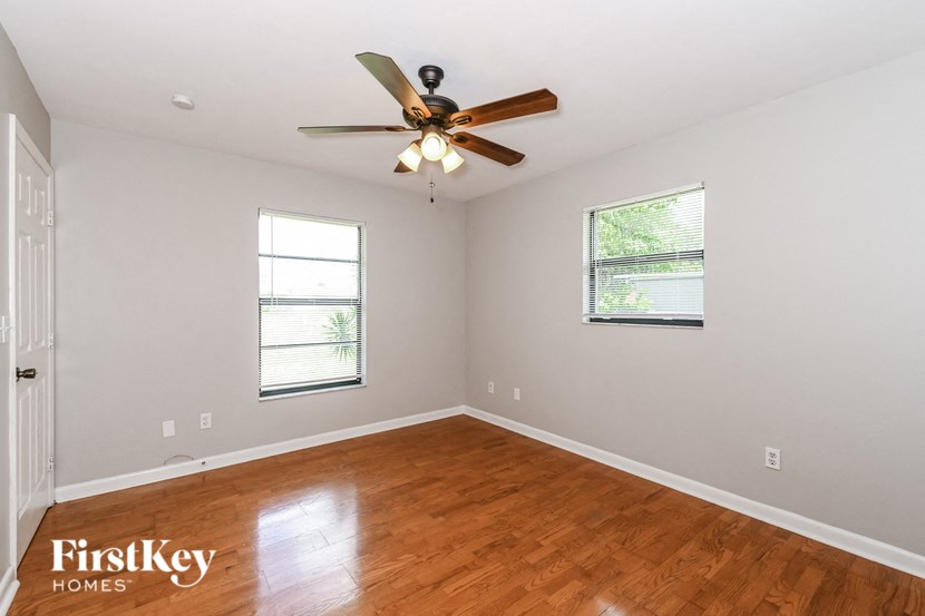 an empty living room with a ceiling fan and wood floors