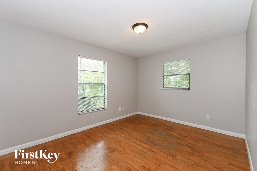 an empty room with a wood floor and two windows