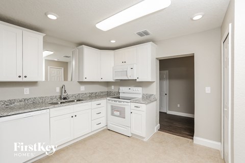 a kitchen with white cabinets and granite counter tops