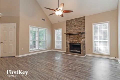 A spacious living room with a fireplace and a ceiling fan.