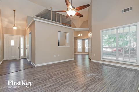 A spacious room with a ceiling fan and wooden flooring.