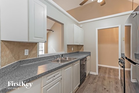 A kitchen with a granite countertop and white cabinets.