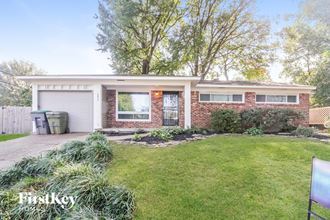 a small brick house with a lawn and a white garage door
