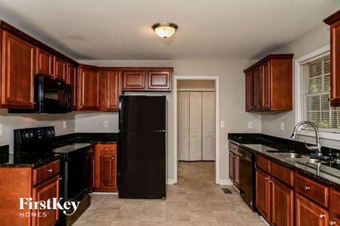 a kitchen with black counters and black appliances and wooden cabinets
