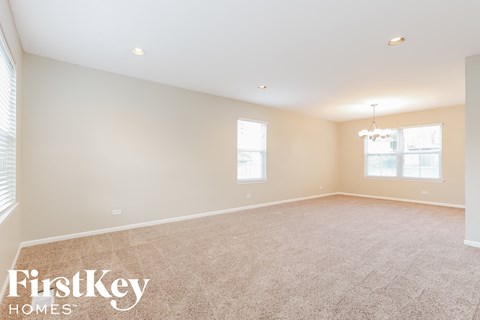 a spacious living room with carpeting and a chandelier