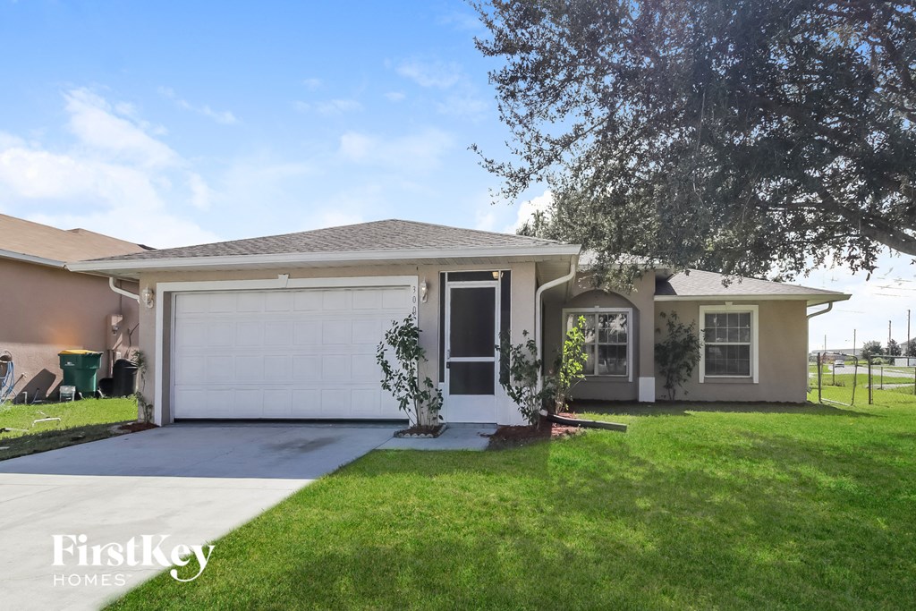A house with a garage and a tree in front of it.