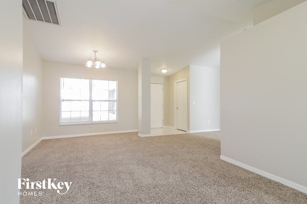 A spacious room with a carpeted floor and a window letting in natural light.