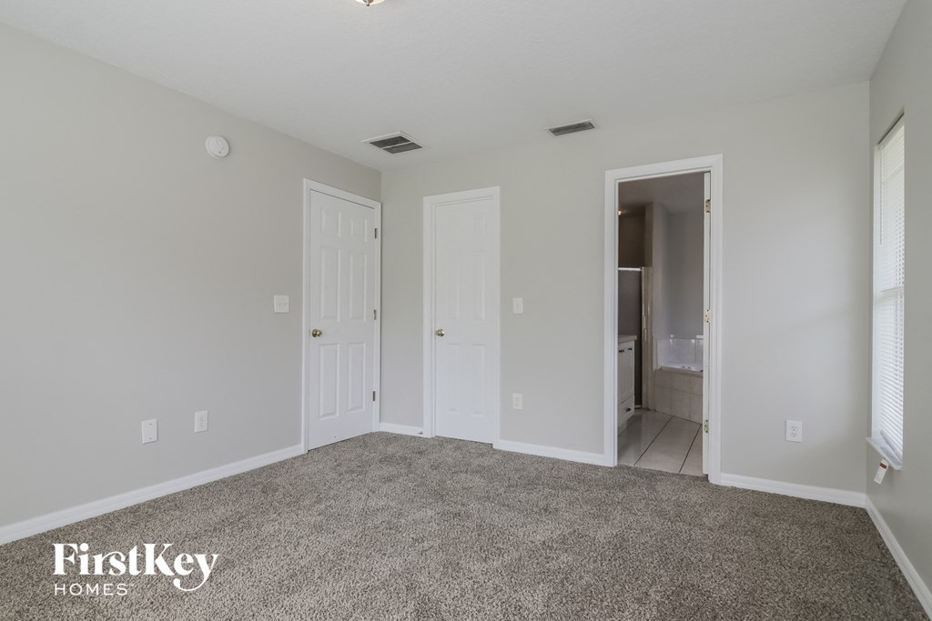 A room with a carpeted floor and two doors.