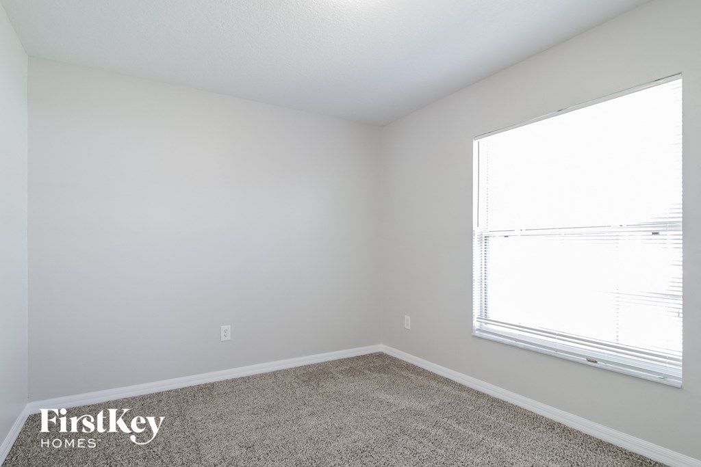 A room with a carpet floor and a window letting in light.