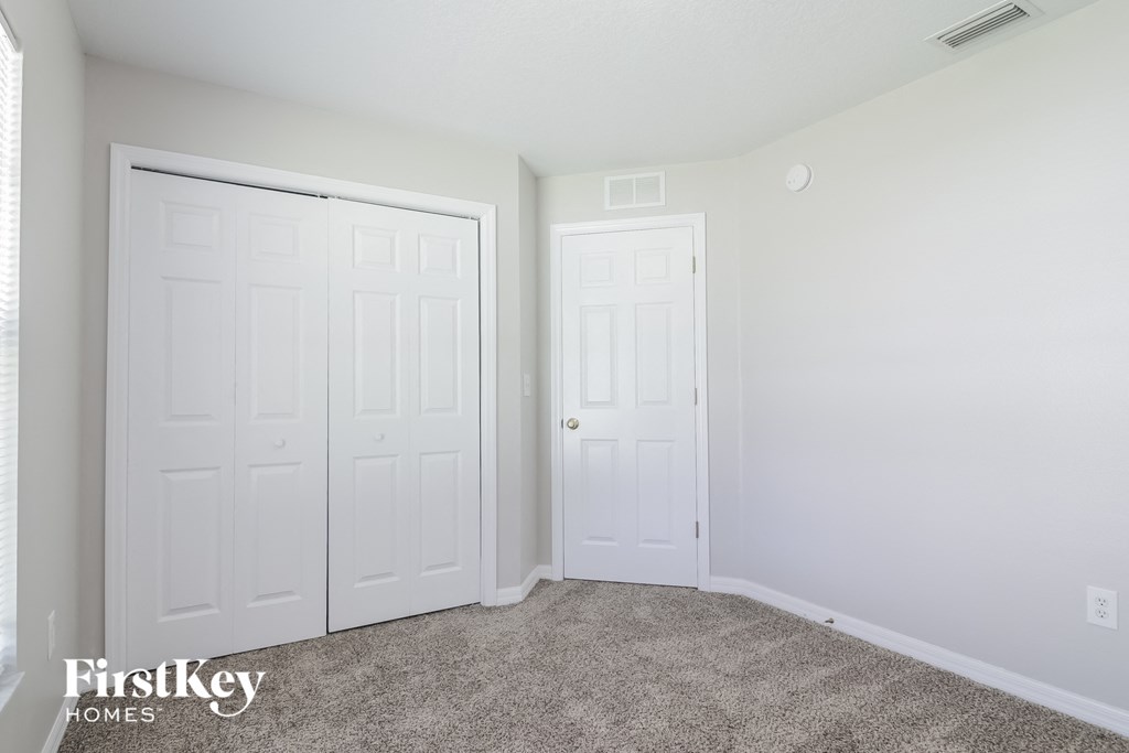 A carpeted room with two doors and a FirstKey Homes logo.