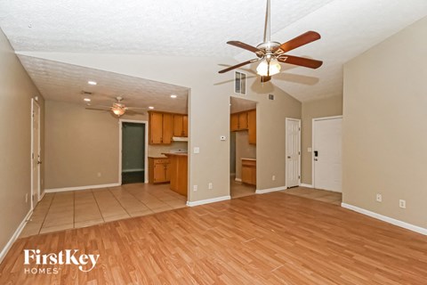 an empty living room with a ceiling fan and wood floors