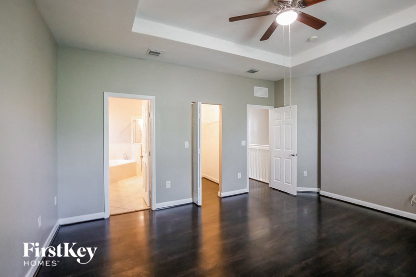 an empty living room with wood floors and a ceiling fan