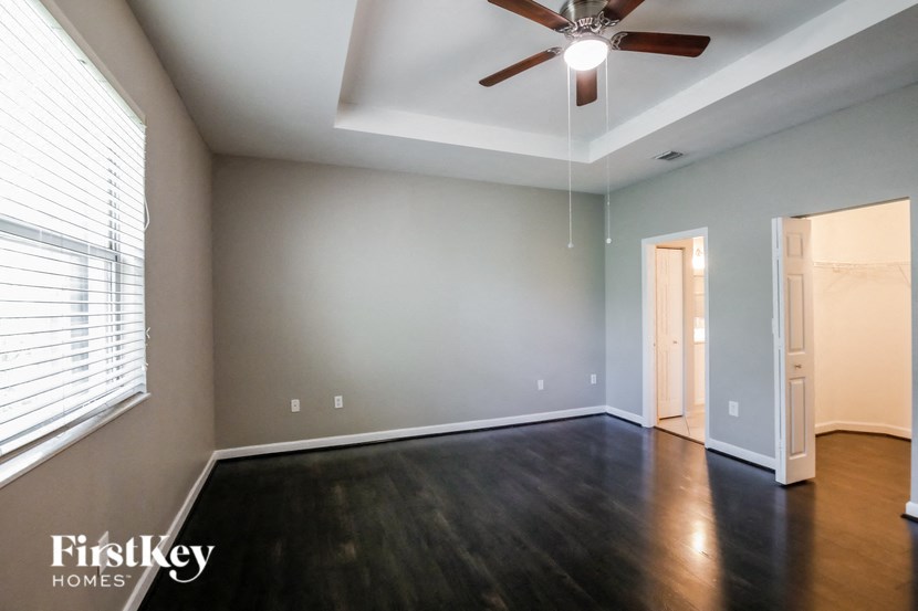 a empty living room with wood floors and a ceiling fan