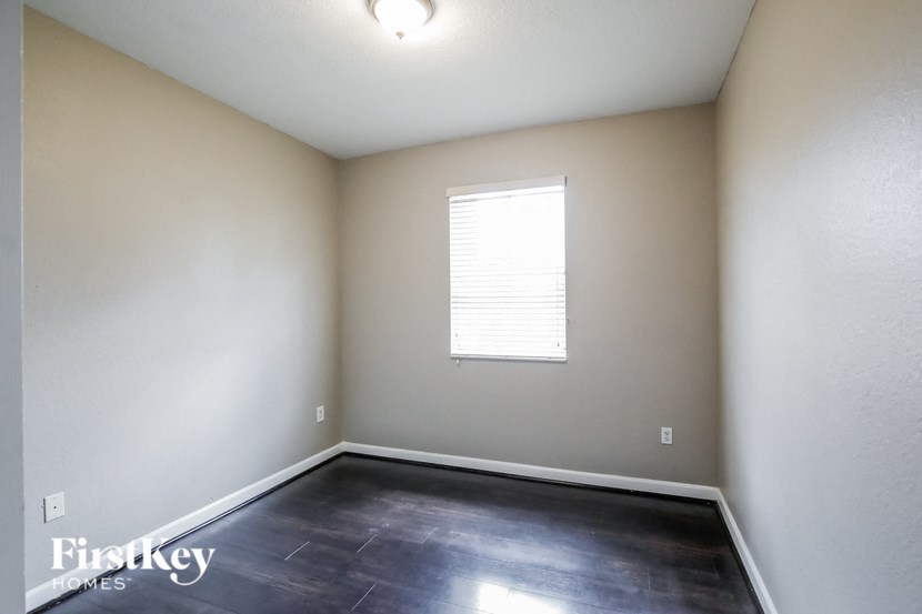 the living room of an empty room with dark flooring and a window