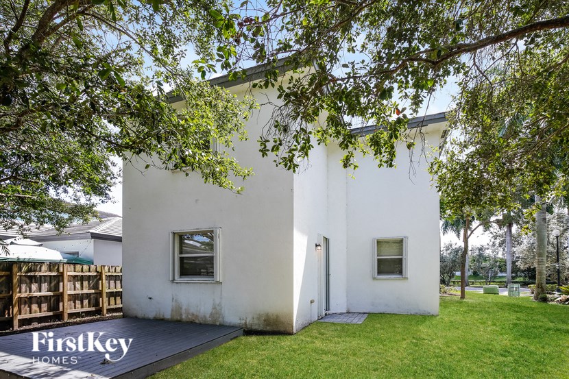 a white house with a deck and a tree