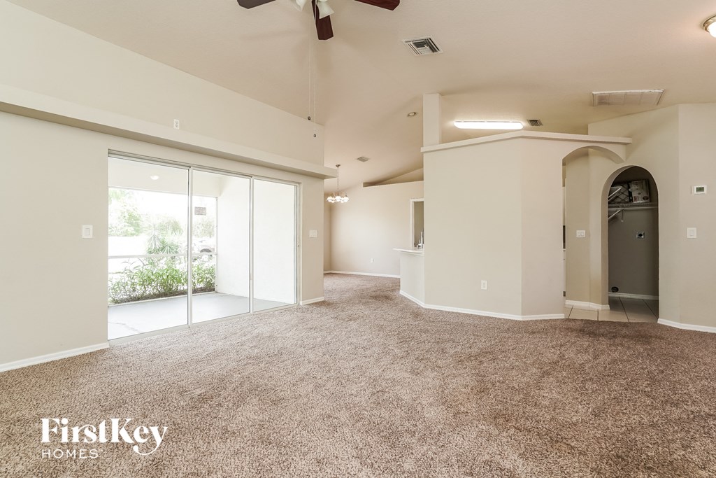 an empty living room with a ceiling fan and a door to a patio
