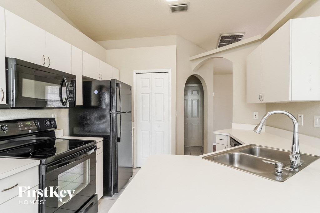 a white kitchen with black appliances and a sink