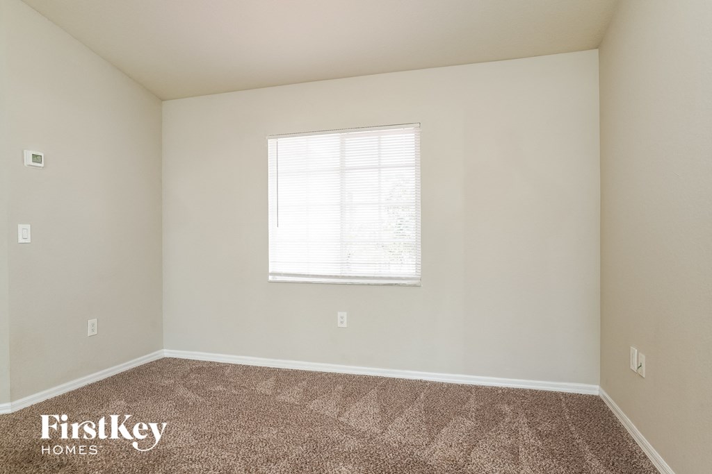 a spacious room with carpet and a window