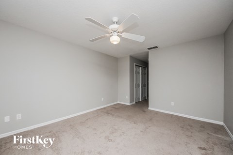 a spacious living room with carpet and a ceiling fan