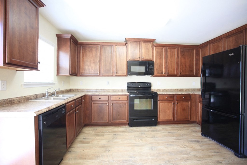 A kitchen with black appliances and wooden cabinets.