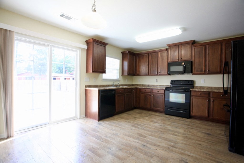 A kitchen with wooden cabinets and black appliances.