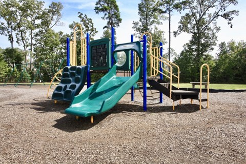 A playground with a green slide and yellow handrails.