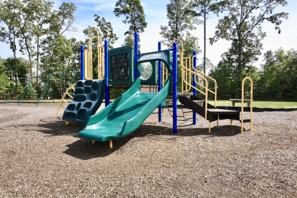 A playground with a green slide and yellow handrails.