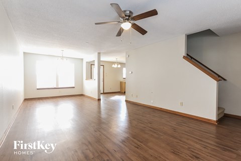 A spacious room with wooden floors and a ceiling fan.