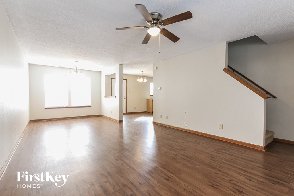 A spacious room with wooden floors and a ceiling fan.