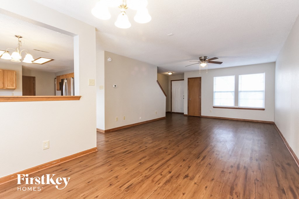 A spacious room with wooden floors and a ceiling fan.