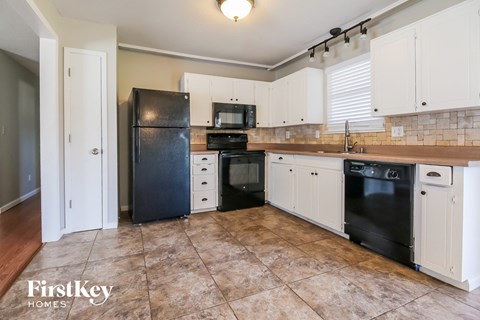 A kitchen with black appliances and white cabinets.