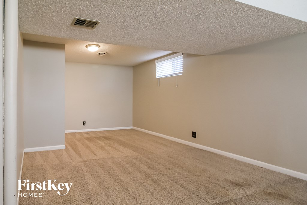 A room with a carpeted floor and a window with blinds.