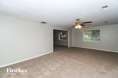 a living room with carpet and a ceiling fan