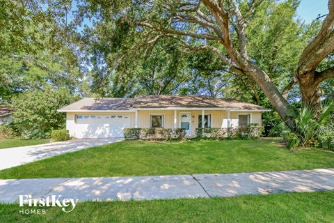a white house with a lawn and trees