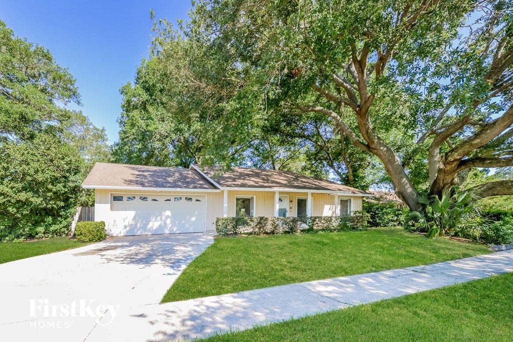 a white house with a lawn and a tree
