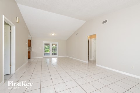 a spacious living room with tiled flooring and white walls