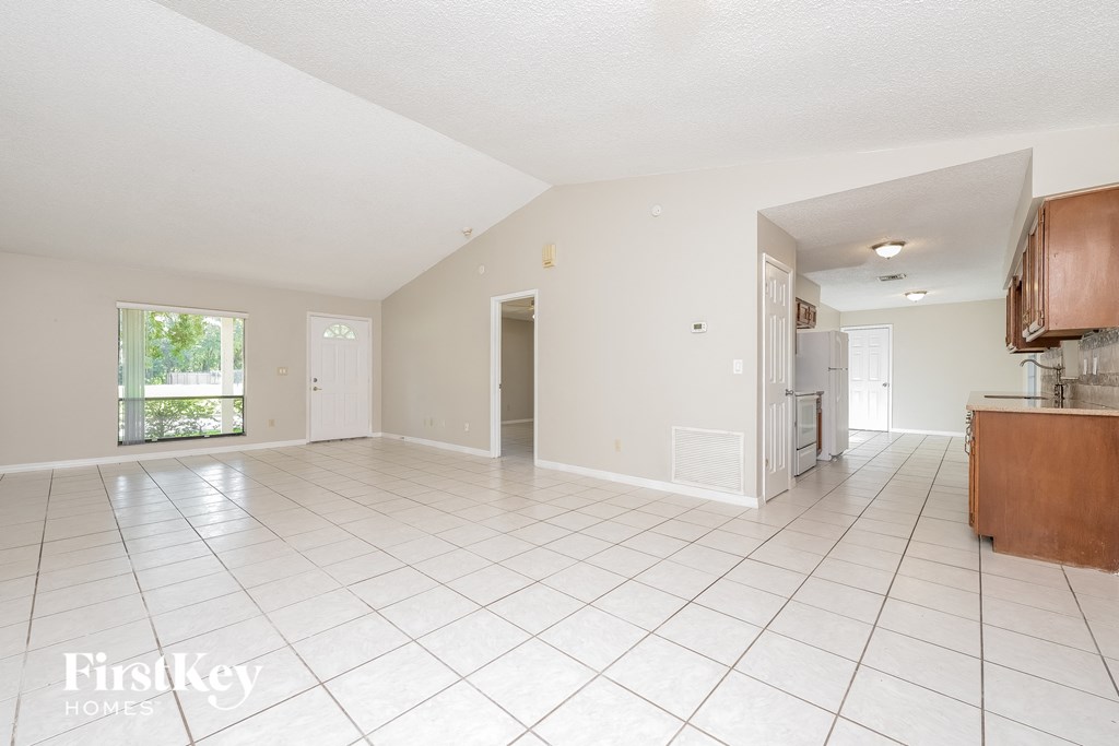 an empty kitchen and living room with white tiled flooring