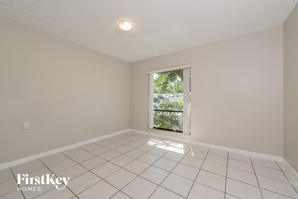 the living room has a large window and white tile flooring