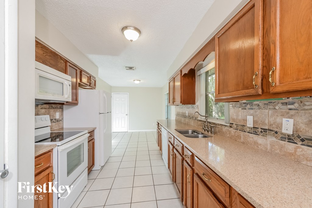 a kitchen with wooden cabinets and white tile floors and a sink