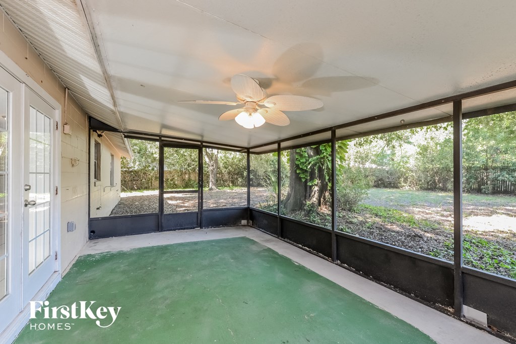 the screened in porch has a ceiling fan and a view of the backyard