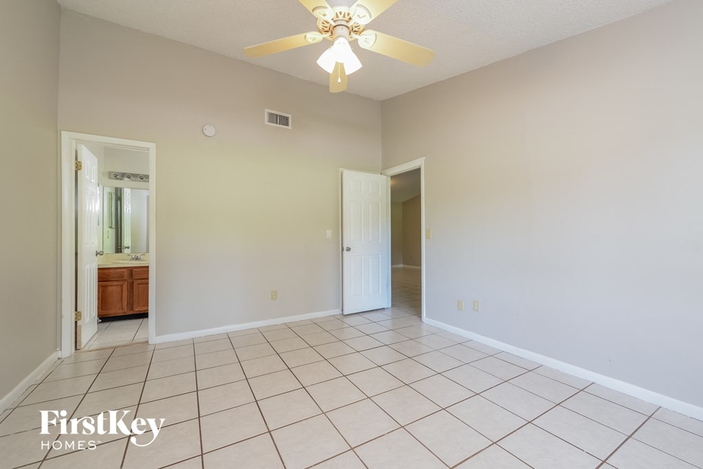 an empty living room with a ceiling fan and a tiled floor