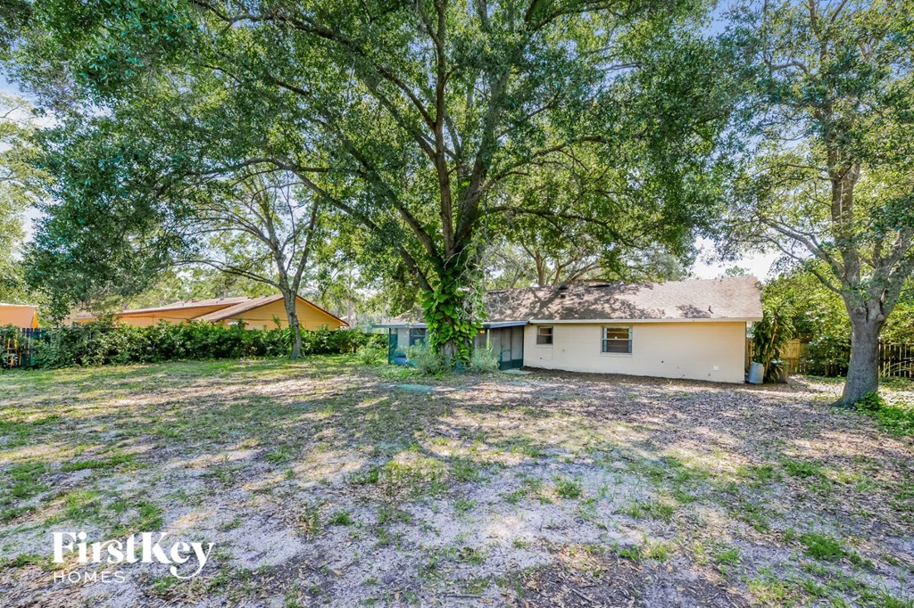 a backyard with trees and a white house
