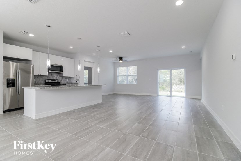 an empty kitchen and living room with a refrigerator and a sink