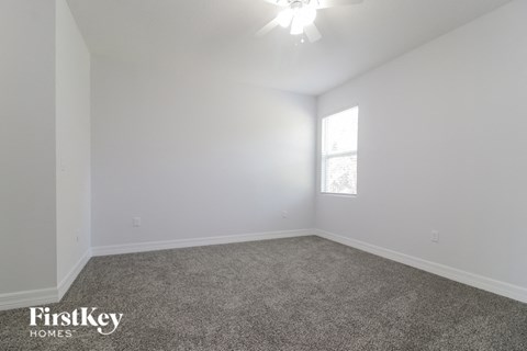a bedroom with white walls and carpet and a window