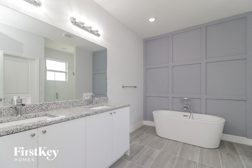 a white bathroom with a tub and a sink and a mirror