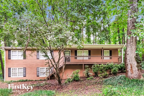 a house in the woods with trees and a deck