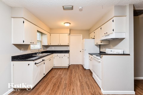 A kitchen with white cabinets and black countertops.