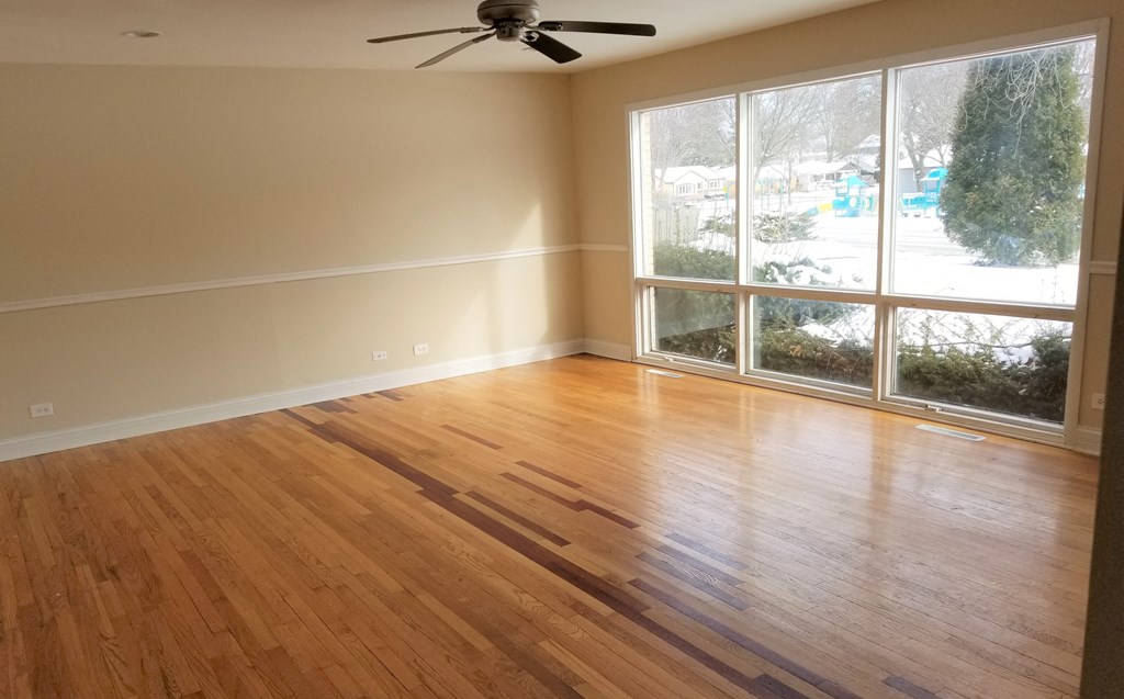 an empty living room with wood floors and a large window